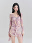 Woman wearing a purple and pink tie-dye mesh cover-up with a tie-front detail and ruffled hem.