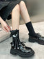 Full view of a person wearing black socks with a black and white eye and tentacle-like attachments, paired with black platform shoes.