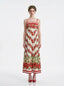 Woman wearing a floral print maxi dress with spaghetti straps, standing against a white background.