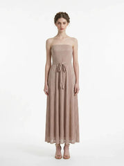 Woman wearing a strapless, metallic knit maxi dress with a self-tie belt, standing against a white background.