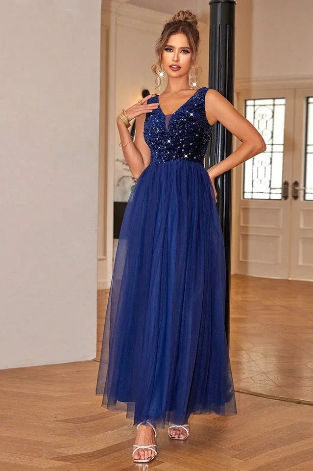 Woman wearing a floor-length royal blue sequined V-neck sleeveless gown with a flowing tulle skirt