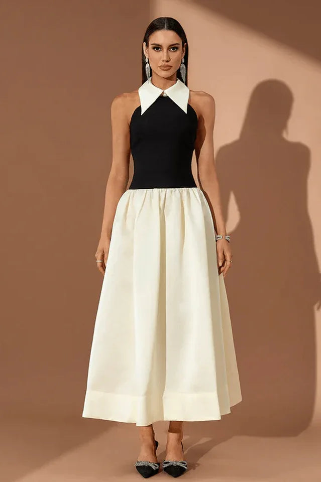 Woman wearing a black and ivory halter gown with a large collar, standing against a brown background.