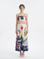 Woman wearing a white sleeveless maxi dress with a colorful graphic print and spaghetti straps, front view