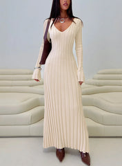 Woman wearing a cream ribbed knit maxi dress with long sleeves and a v-neckline, accessorized with a brown shoulder bag, silver necklace, and silver bracelet.