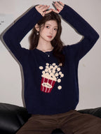 Woman wearing a navy blue knit sweater with a popcorn graphic and Korean text, with hands raised.