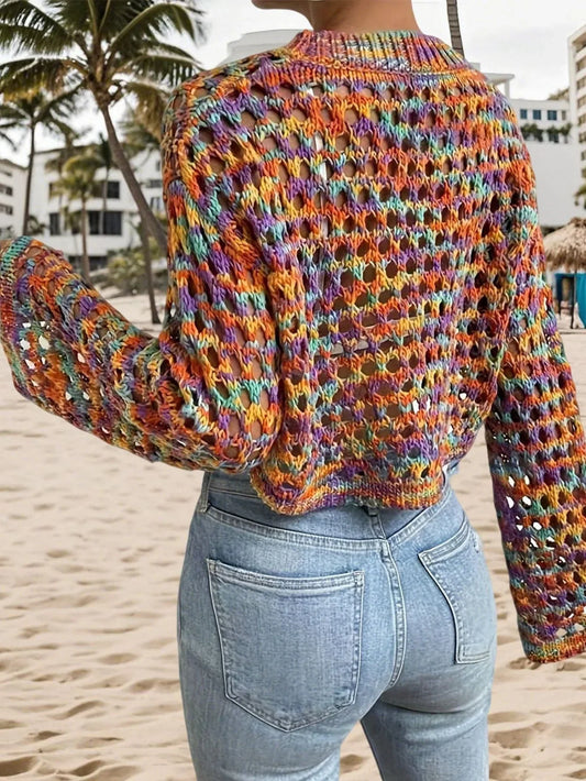 Back view of a woman in a multicolored open-knit cropped sweater and light-wash denim jeans.
