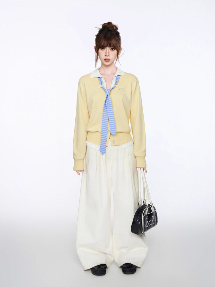 Woman posing with hands in pockets, wearing a yellow knit cardigan and cream wide-leg pants.