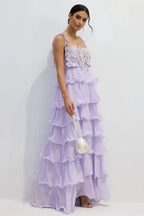 Side view of a woman in a light purple ruffled chiffon maxi dress with a floral applique bodice.