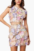Close-up of a woman wearing a floral applique crop top and mini skirt, showing detailed embroidery.