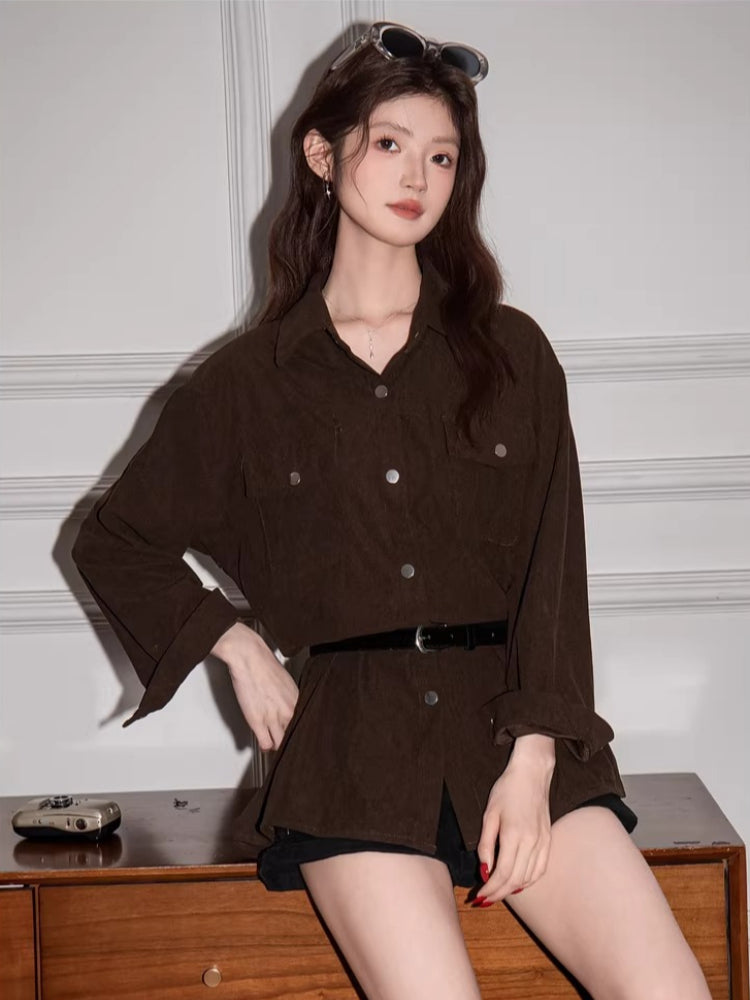 Woman sitting on a wooden surface wearing a brown corduroy shirt dress