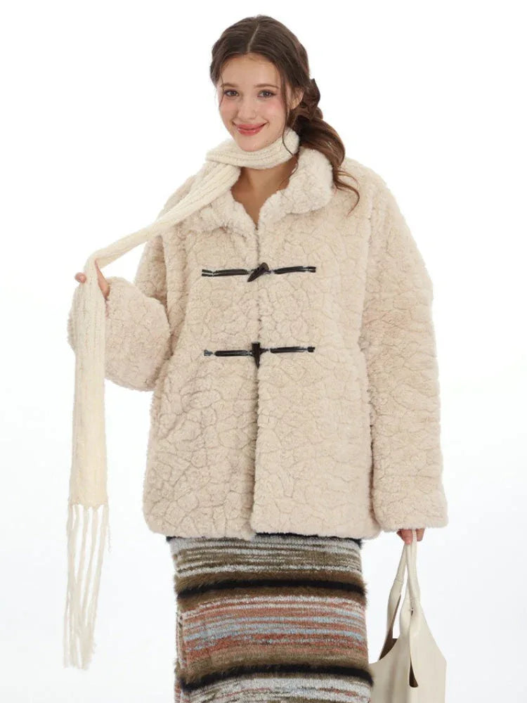 Close-up of a woman wearing a cream-colored fleece coat with toggle closures and a cream scarf, smiling.