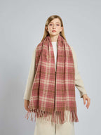 Woman wearing a pink and tan plaid scarf over a cream coat.