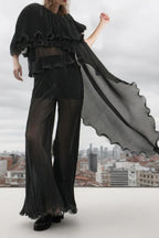 woman wearing a black pleated ruffled top and wide-leg pants