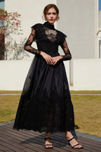 Full-length view of a woman in a black lace and satin formal gown.