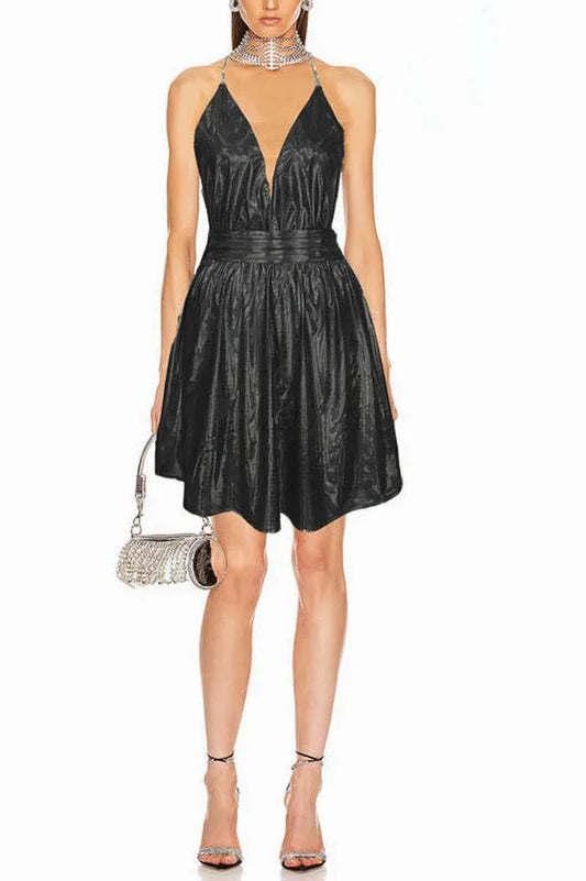 Woman wearing a short black halter dress with a deep V-neck and A-line skirt, accessorized with a sparkly clutch and heels.