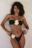 Model posing in a black strapless bikini with floral accents.