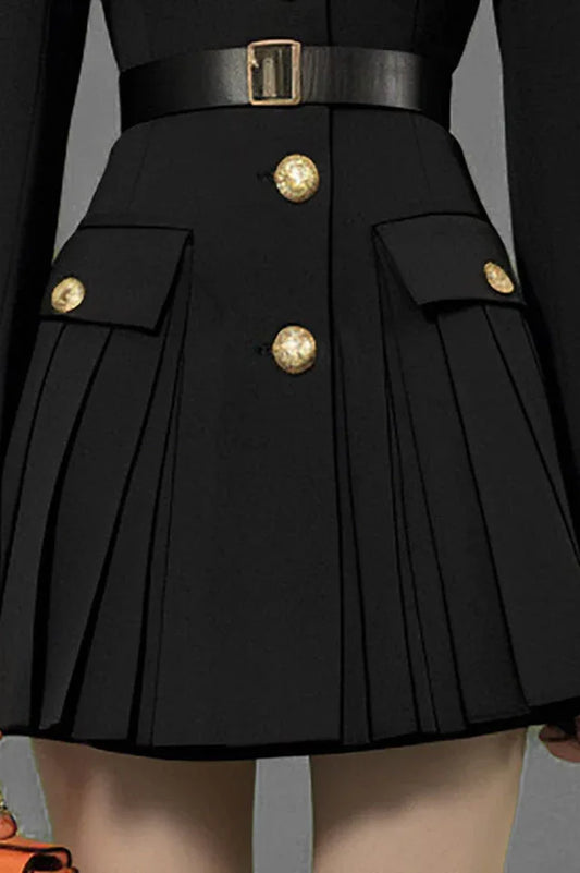 Close-up of pleated skirt and gold buttons on black dress