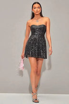 Woman wearing a black sequined strapless dress with a sweetheart neckline and A-line skirt, full body view