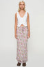 Front view of a woman in a white sleeveless vest and a pink floral maxi skirt.