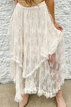 A woman wearing a white lace tiered ruffle skirt with tan boots.