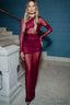 Woman in a burgundy sheer mesh gown with a cut-out and long sleeves.
