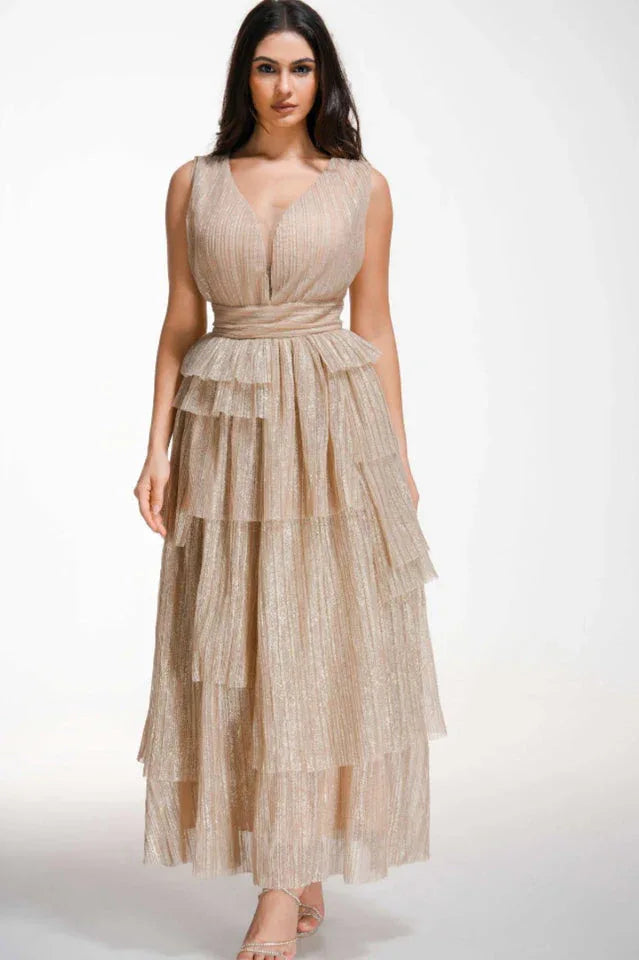 Woman wearing a floor-length, sleeveless, champagne-colored sparkly tiered gown with a V-neckline and empire waist. Main image