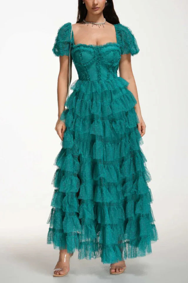 Woman wearing a floor-length emerald green tiered tulle gown with puff sleeves and a sweetheart neckline.