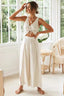 Woman wearing a cream linen-blend sleeveless v-neck ruched drawstring crop top and matching wide leg pants with side slits and tie waist.