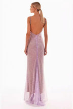 A woman models a sparkling lavender floor-length gown with a cowl neckline and spaghetti straps, back view.