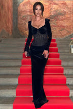 woman in a long black off-the-shoulder velvet dress with a sparkling corset bodice on a red carpet