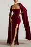 Model posing in a maroon formal dress with a high leg slit and dramatic cape sleeves.