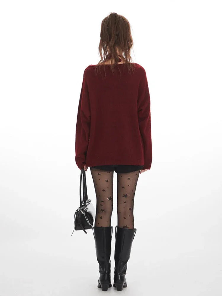 Back view of a woman wearing a burgundy layered sweater with black bows, black star-patterned tights, and black boots, holding a black handbag.