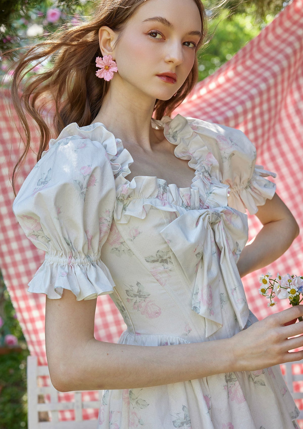 Flat lay of a white floral print off-the-shoulder tiered dress with puffed sleeves and a bow detail
