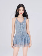 Woman wearing a light blue ruffled halter dress with a floral pattern and a layered skirt.