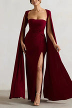 Woman wearing a floor-length maroon gown with a sweetheart neckline, cape sleeves, and a high leg slit.