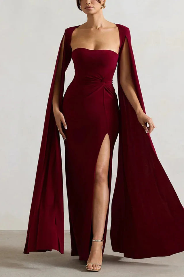 Woman wearing a floor-length maroon gown with a sweetheart neckline, cape sleeves, and a high leg slit.