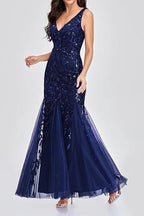 Woman wearing a floor-length navy blue sequined mermaid gown from the side, showcasing the silhouette.