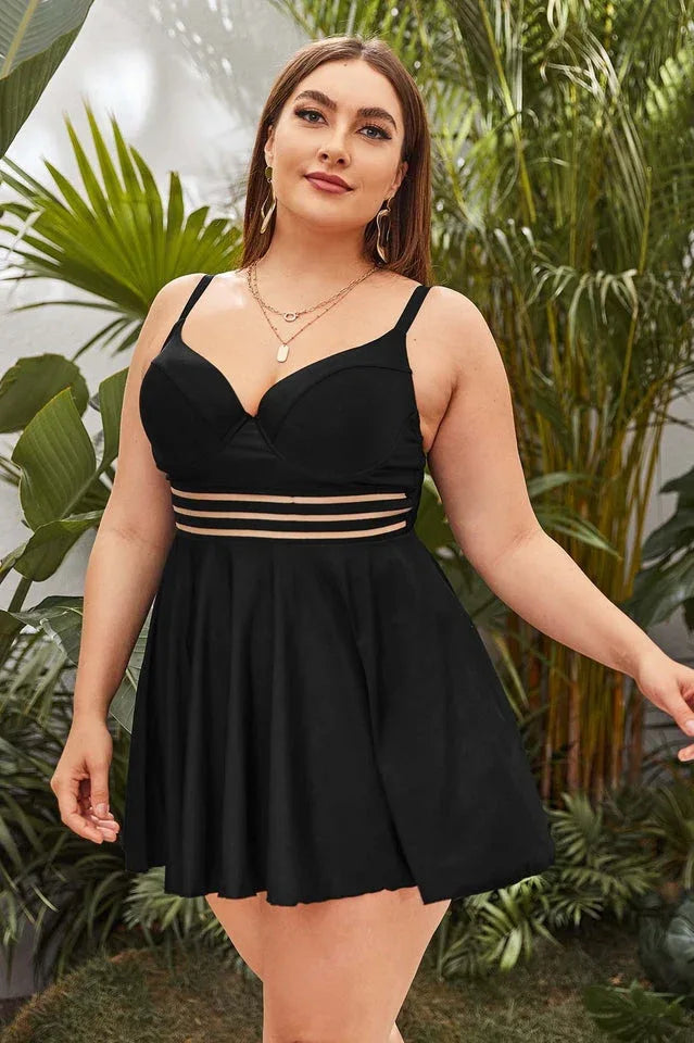 Plus-size black one-piece swimsuit with a flared skirt, worn by a model standing outdoors with lush greenery in the background. Main image