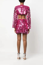 Full back view of a woman wearing a pink sequined crop top with bell sleeves and a matching mini skirt.