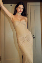 Close-up of a woman in a shimmering gold strapless formal gown, highlighting the ruched bodice.