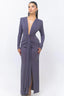Woman wearing a long, dark purple, sparkly dress with a deep V-neck and long sleeves, standing against a white background.
