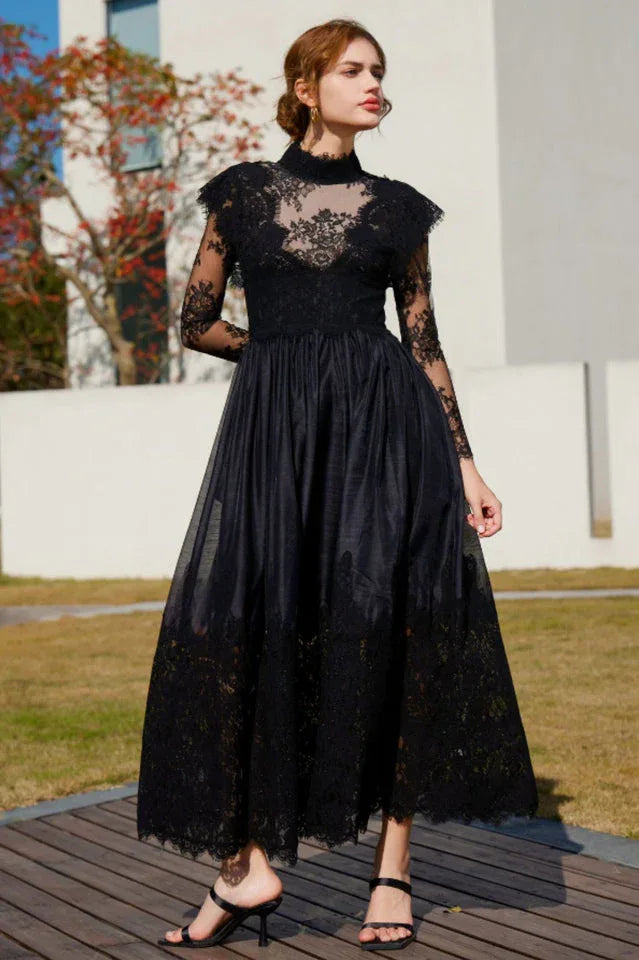 Woman wearing a black lace and satin formal dress with long sleeves and a high neckline, standing outdoors. Main image