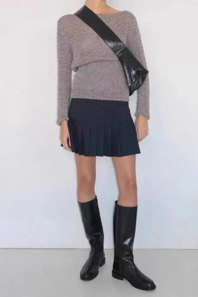 Woman wearing a grey long-sleeved top, a black pleated mini skirt, and black knee-high boots with a black shoulder bag. Main image