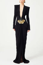 Black long-sleeved gown with a plunging V-neckline and a draped skirt, featuring a jeweled butterfly embellishment at the waist.