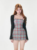 Woman wearing a plaid mini dress and a sheer black cardigan.