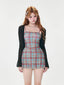 Woman wearing a plaid mini dress and a sheer black cardigan.