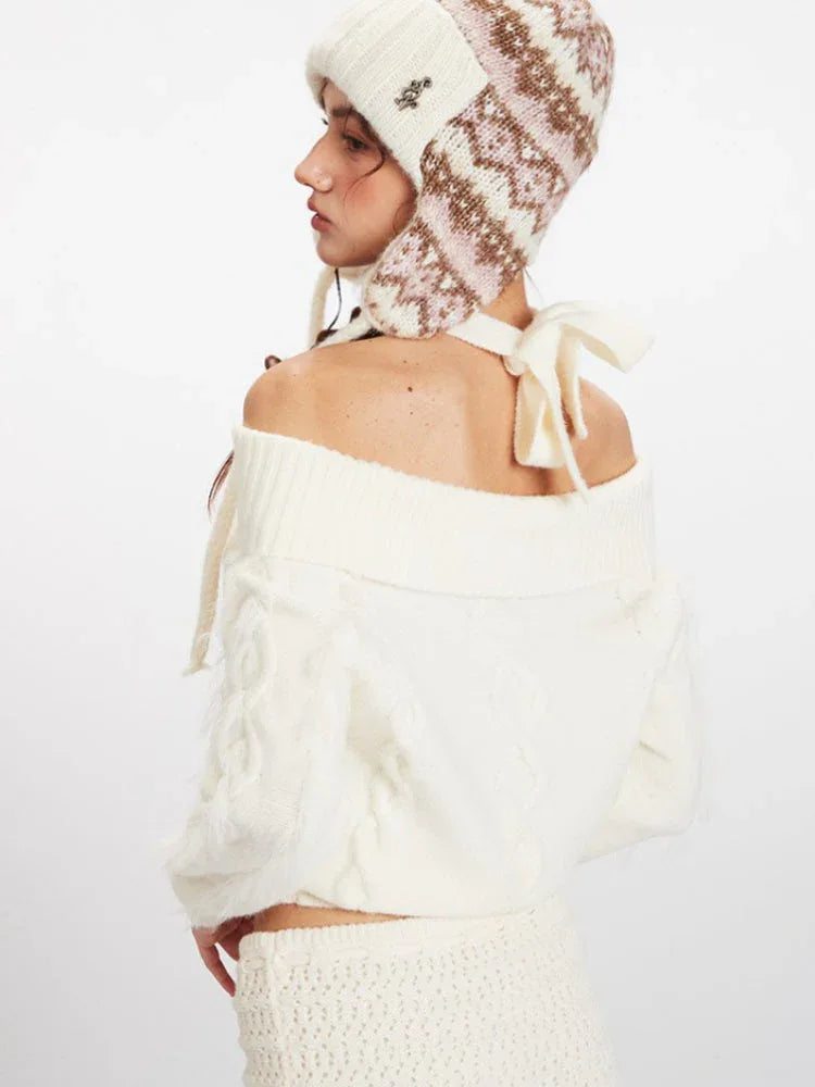 Back close-up of a model wearing a cream off-the-shoulder knit sweater and a matching mini skirt, with an ear flap hat and pink handbag.