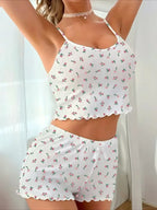 Close-up of a woman's torso wearing a white floral print pajama set with spaghetti straps and ruffled hem.