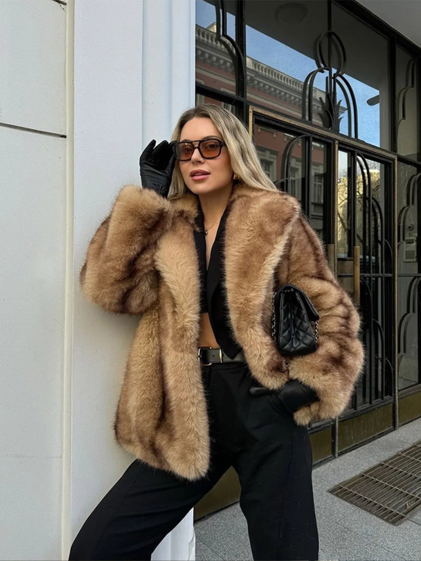 Woman wearing a tan and brown faux fur cropped jacket with black pants and black gloves. Main image