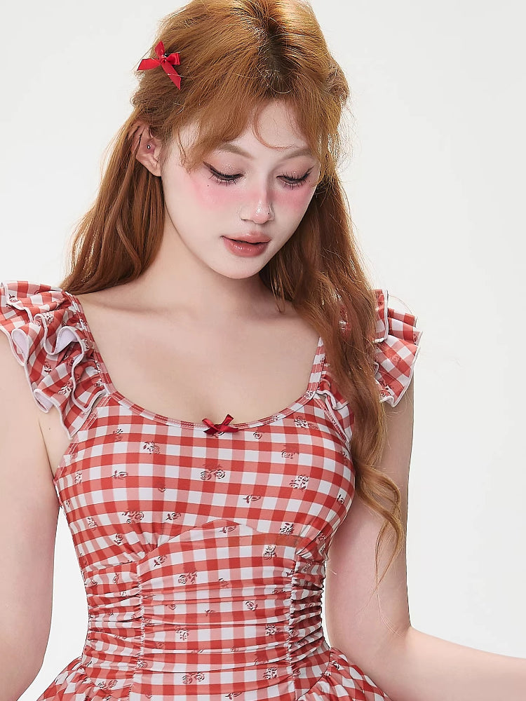 Close-up of a woman wearing a red and white gingham dress with a scoop neckline and ruffled sleeves.